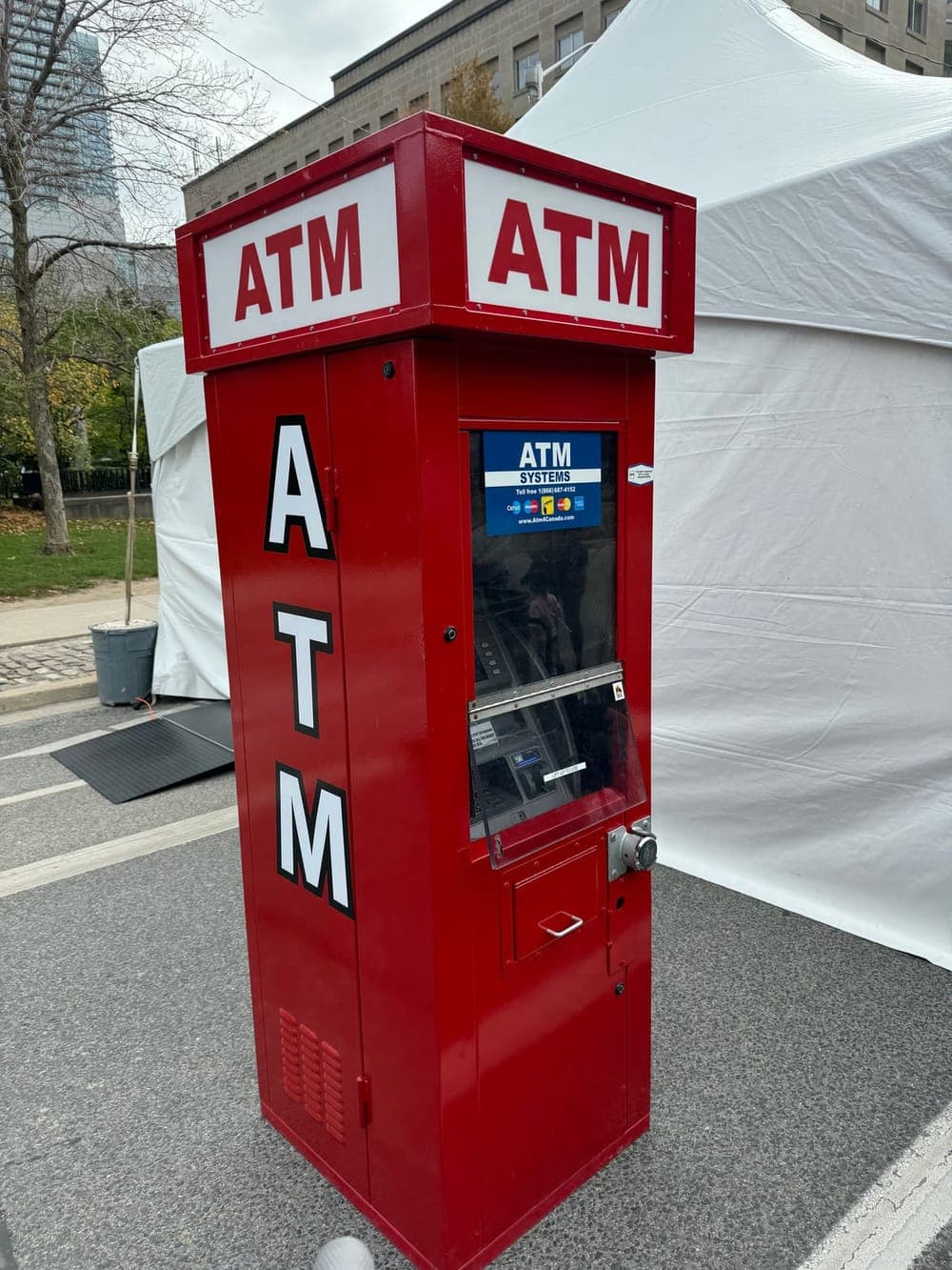 Free-standing red event ATM kiosk set up outdoors beside event tents
